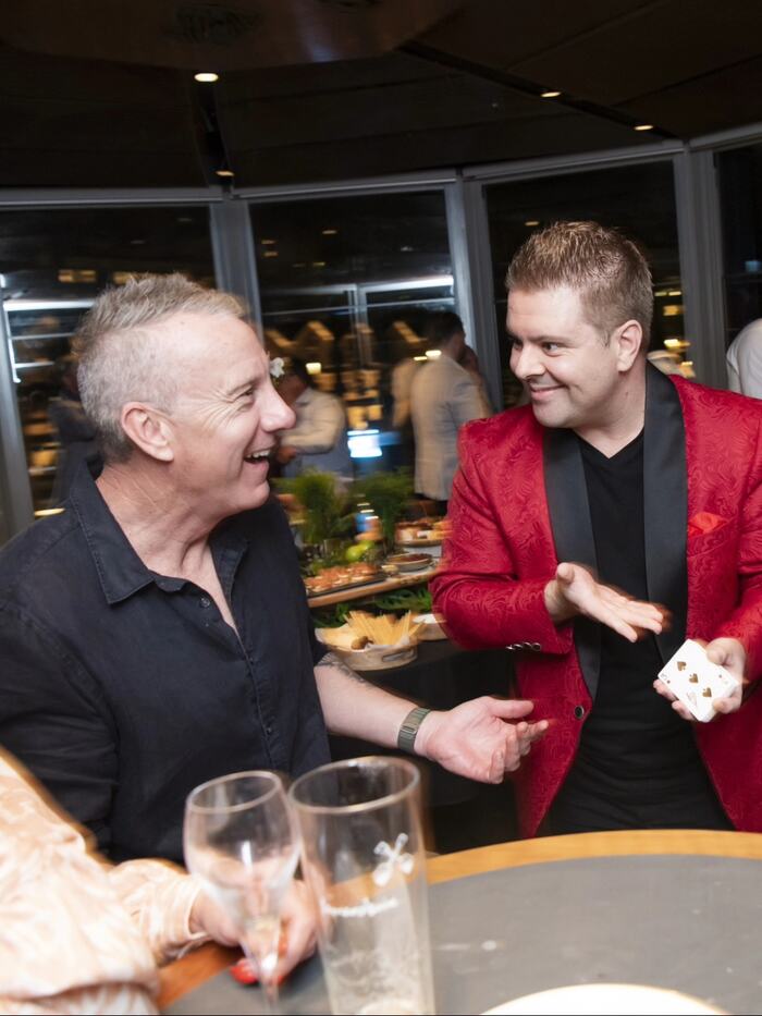Guests reacting with amazement at John Messina's close-up magic